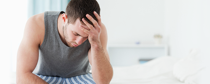 Guy sitting on Bed thinking 